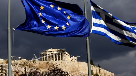 A European Union flag, left, and Greek national flag fly near the Parthenon temple on Acropolis hill in Athens, Greece.